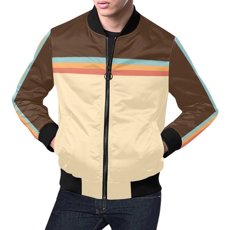 May include: A bomber jacket with a cream-colored front and brown upper section. The jacket features horizontal stripes in orange, blue, and yellow. The sleeves have matching stripes. It has a black zipper and black cuffs and hem.