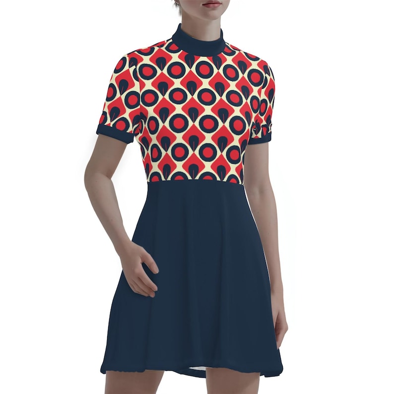 May include: A short-sleeved dress featuring a retro geometric pattern in red, black, and cream on the bodice. The dress has a high neckline and a solid navy blue skirt. The dress is knee-length and has a fitted bodice and a flared skirt.