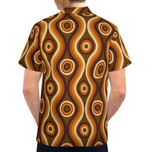 Pu&ograve; includere: Una camicia a maniche corte con bottoni e un motivo retr&ograve; anni '70 con linee ondulate e cerchi marroni, arancioni e crema.