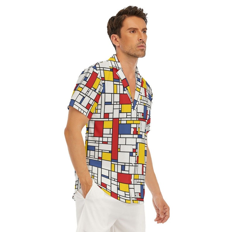 Puede incluir: Una camisa de manga corta con botones y un patr&oacute;n geom&eacute;trico en rojo, amarillo, azul y blanco. La camisa tiene cuello y un ajuste holgado.