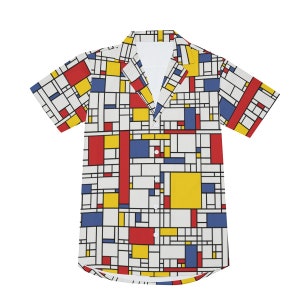 Puede incluir: Una camisa blanca de manga corta con botones y un patr&oacute;n geom&eacute;trico en rojo, amarillo y azul.