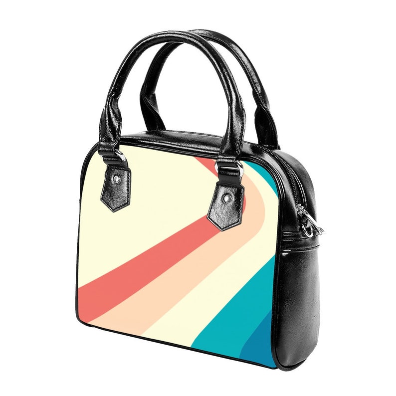 K&ouml;nnte beinhalten: Eine schwarze Handtasche mit Rei&szlig;verschluss und einem oberen Henkel. Die Tasche hat ein farbenfrohes abstraktes Design mit geschwungenen Linien in den Farben Rosa, Gelb und Blau.