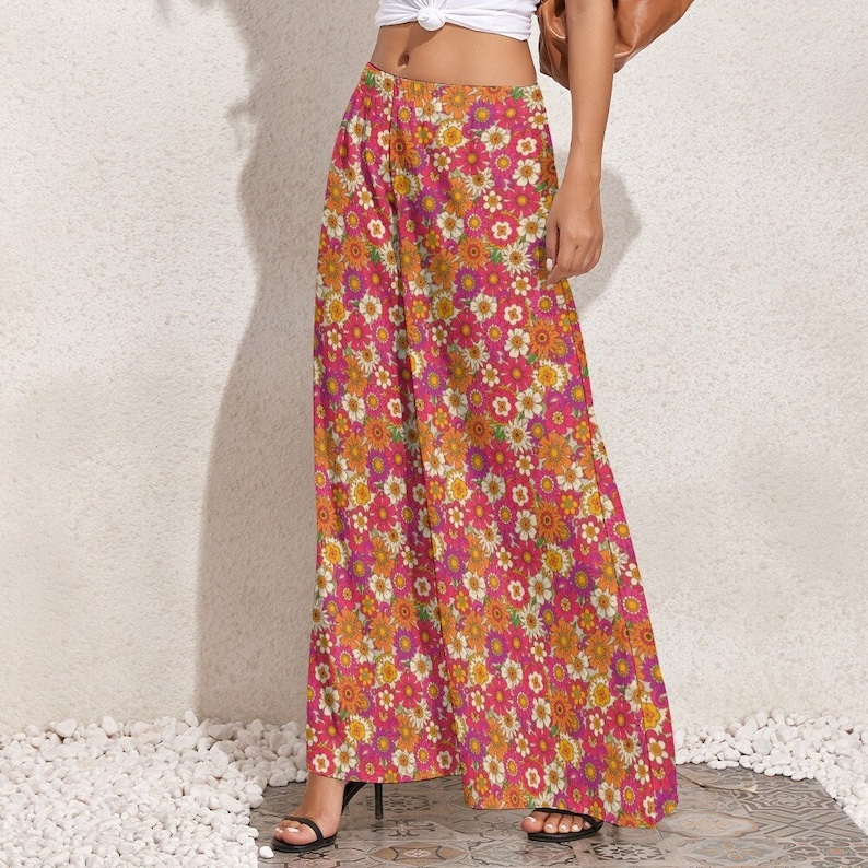 Puede incluir: Pantal&oacute;n de pierna ancha con estampado floral en tonos rosa, naranja y amarillo. El estampado presenta una variedad de flores, incluyendo margaritas y rosas.
