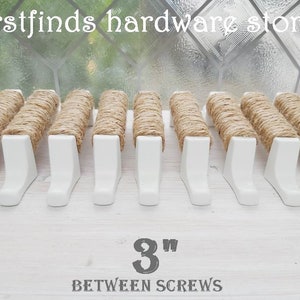 May include: A row of 12 white shelf brackets with jute rope wrapped around the top. The brackets are 7.6 cm apart. The text "firstfinds hardware store" and "3" inches between screws" is visible in the image.