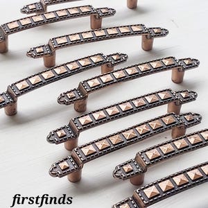 May include: Bronze-coloured cabinet handles with a square pattern. The handles are arranged on a white surface. The text "firstfinds hardware store" is visible in the lower left corner.