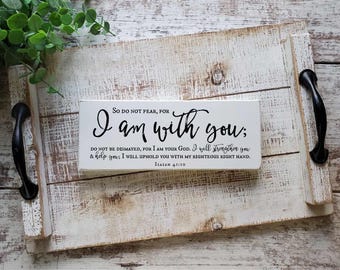 May include: A rectangular white wooden sign with black text that reads: So do not fear, for I am with you; do not be dismayed, for I am your God. I will strengthen you & help you; I will uphold you with my righteous right hand. Isaiah 41:10.