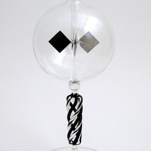 May include: A glass globe with a black and white propeller inside, mounted on a black and white twisted glass stem and a clear glass base.