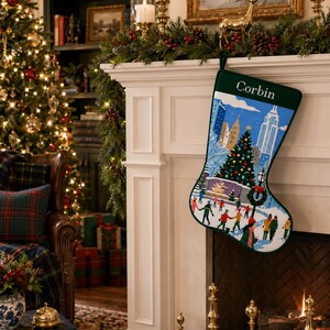 May include: A dark green Christmas stocking featuring the name Corbin in white text at the top. The body of the stocking displays a colourful, detailed scene of people ice skating in a city park with tall buildings and a large decorated tree.
