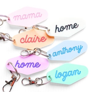 May include: Six colorful motel keychains with different names on them, including "mama", "claire", "home", "anthony", and "logan".