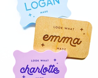 May include: Three rectangular plaques with wavy or straight edges. One light blue plaque reads LOOK WHAT LOGAN MADE with stars. One wooden plaque reads LOOK WHAT emma MADE with stars. One light purple plaque reads LOOK WHAT charlotte MADE with stars.