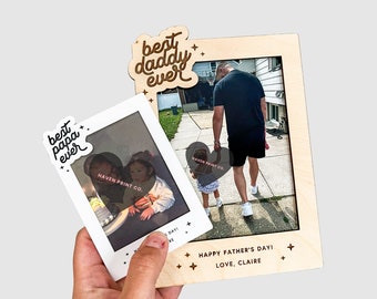 May include: A wooden photo frame with a cutout design that says "best daddy ever" and "best papa ever". The frame has a photo of a father and daughter walking down a sidewalk. The frame also has the text "Happy Father's Day! Love, Claire".