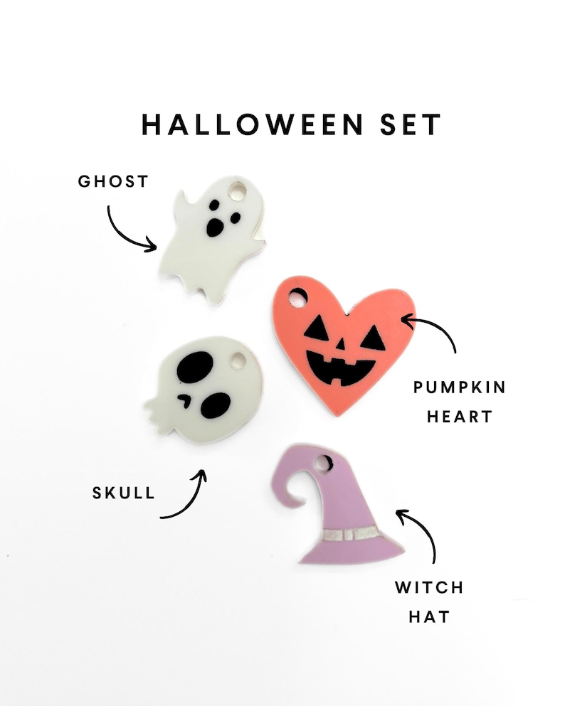 Op de afbeelding: Een set van vier Halloween-thema hangers, waaronder een spook, een schedel, een pompoenhart en een heksenhoed. De hangers zijn gemaakt van wit, zwart, oranje en paars acryl.