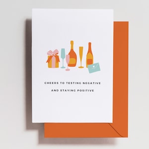 May include: A greeting card with a colorful illustration of champagne bottles, glasses, a gift box, and an envelope. The text on the card reads "Cheers to testing negative and staying positive."