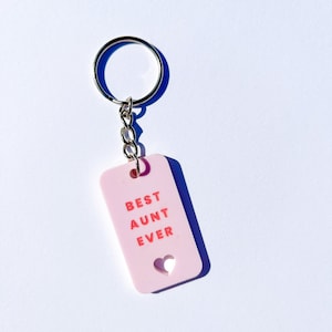 May include: Pink keychain with a silver key ring and a pink tag that says "BEST AUNT EVER" with a heart cutout.