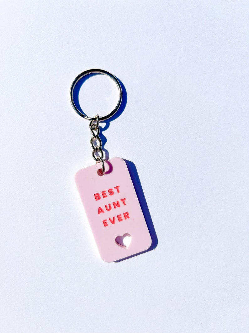May include: Pink keychain with a silver key ring and a pink tag that says "BEST AUNT EVER" with a heart cutout.