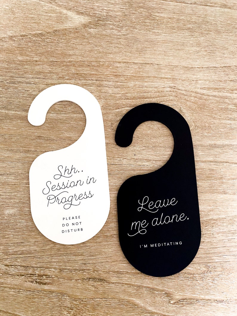 May include: Two door hangers with a hook top. The white hanger features black text reading Shh.. Session in Progress and PLEASE DO NOT DISTURB. The black hanger features white text reading Leave me alone. and I'M MEDITATING in a script and sans-serif font.