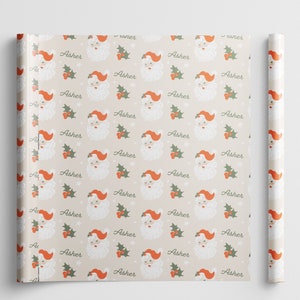 May include: Beige wrapping paper with a repeating pattern of Santa Claus faces with red hats and white beards. The pattern also includes green holly leaves and red berries. The word "Asher" is repeated throughout the pattern.