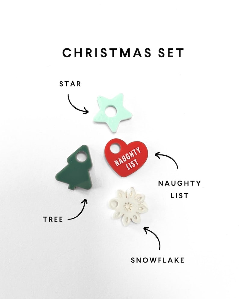 Op de afbeelding: Een kerstset van vijf ornamenten: een groene boom, een rood hart met de tekst "NAUGHTY LIST", een witte sneeuwvlok, een lichtblauwe ster en een witte sneeuwvlok.