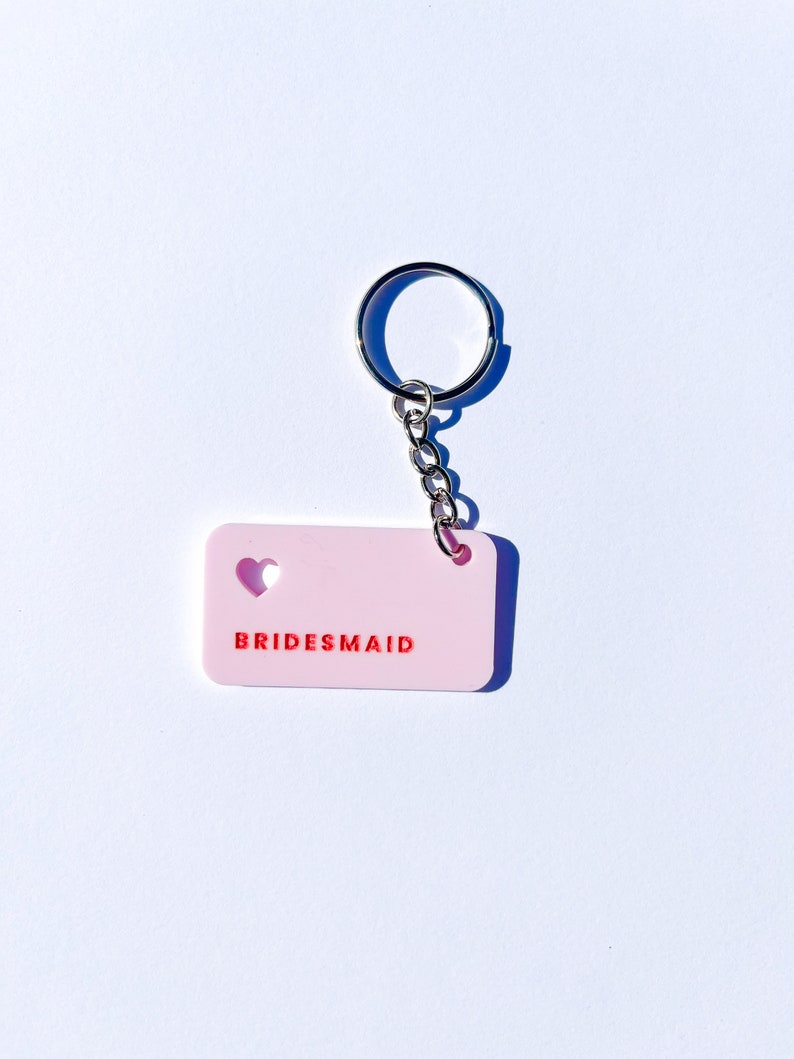 May include: Pink keychain with a heart cut-out and the word "BRIDESMAID" in red lettering.