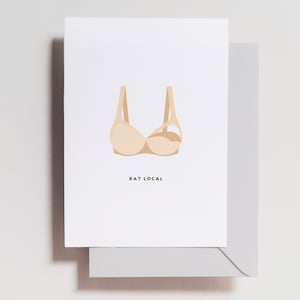 May include: A white card with a beige bra illustration and the text "EAT LOCAL" printed in black.
