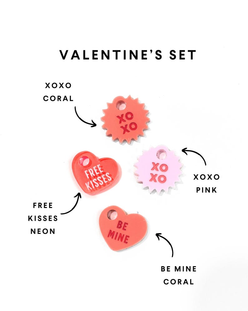 Op de afbeelding: Een set van vier acrylcharms met een Valentijnsdagthema. De charms zijn in de vorm van harten en sterren en bevatten de zinnen "XOXO", "Free Kisses", "Be Mine" en "XOXO". De charms zijn in de kleuren koraal, roze en neon.