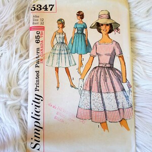 May include: Vintage Simplicity sewing pattern number 5347 for a dress. The pattern is for a size 12, bust 32. The pattern shows three different styles of dresses, all with gingham fabric. The pattern is printed on a white background with black text.