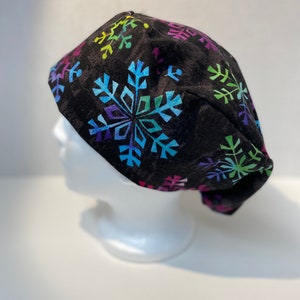 May include: Black scrub hat with a colorful snowflake pattern.