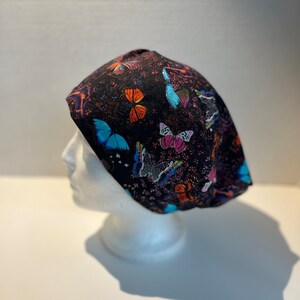 May include: Black scrub hat with a colorful butterfly print. The hat is made of a soft, comfortable fabric and is perfect for healthcare professionals.