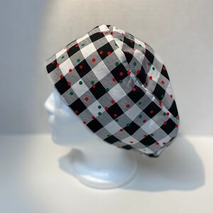 May include: A black and white checkered fabric hat with red and green polka dots.