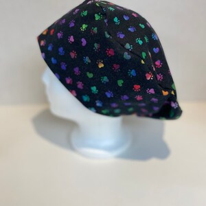May include: Black scrub hat with a rainbow paw print and heart pattern.