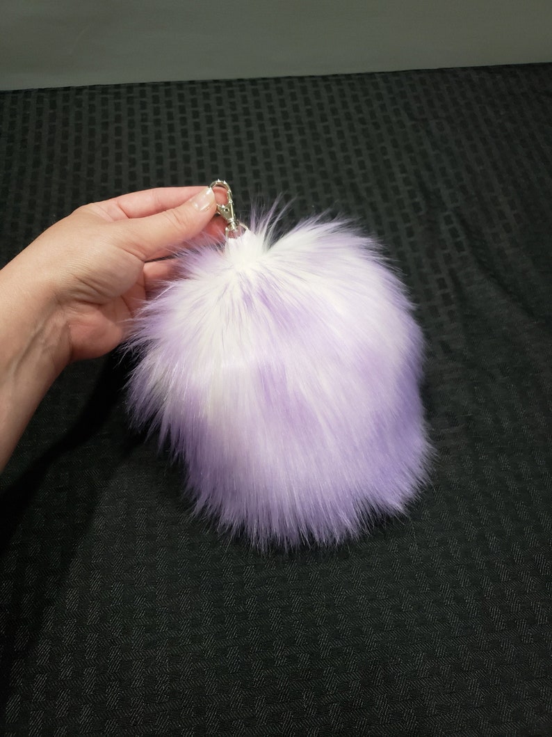 May include: A fluffy purple and white faux fur keychain with a silver metal clasp.