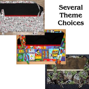 May include: Several fabric organizers with different themes are displayed. One features a black top with a red stripe and a white and gray dog pattern. Another has a black top with a colorful school-themed pattern. The third has a brown top with a raccoon pattern.