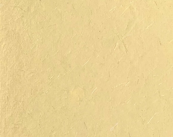 May include: A close-up of a pale yellow textured surface with subtle lines and flecks throughout.
