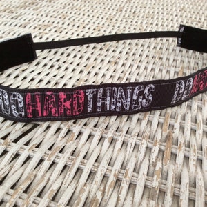Puede incluir: Diadema negra con texto blanco y rosa que dice "DO HARD THINGS DAILY".