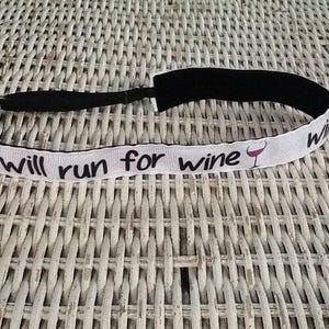 May include: White headband with black elastic and the text "Will run for wine" with a red wine glass icon.