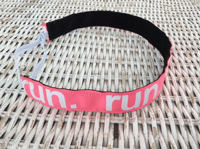 Puede incluir: Diadema rosa con banda el&aacute;stica negra y texto blanco que dice "run".