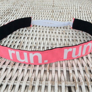 Puede incluir: Diadema rosa con el&aacute;stico negro y texto blanco que dice "run. run".