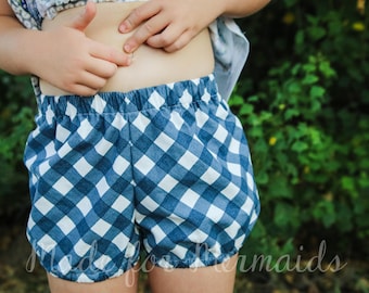 May include: A child wearing blue and white gingham shorts with a white elastic waistband.
