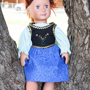 May include: A doll with red hair wearing a blue and black dress with a floral pattern. The doll is sitting in a tree.