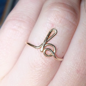 May include: A gold-coloured ring with a simple, stylised letter 'b' design.
