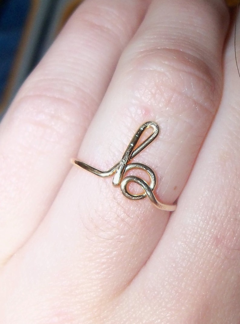 May include: A gold-coloured ring with a simple, stylised letter 'b' design.