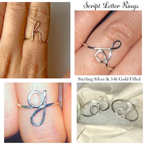 May include: Two silver script letter rings, one with the letter 'g' and the other with the letter 'd'. The rings are on a white surface. Script Letter Rings Sterling Silver & 14k Gold Filled.