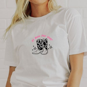 Könnte beinhalten: Weißes T-Shirt mit einer pinkfarbenen Grafik von Cowboystiefeln und dem Text "Pi Beta Phi 1867"