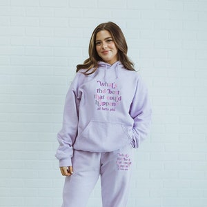 Könnte beinhalten: Ein helllila Hoodie und Jogginghosen-Set. Der Hoodie hat eine Vordertasche und den Text "What's the best that could happen pi beta phi". Die Jogginghose hat auch den gleichen Text. Die Person trägt weiße Turnschuhe.