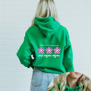 May include: Green hooded sweatshirt with the text "be in love with every minute of your life" and three pink and white flowers. Below the flowers is the text "Phi sigma sigma".