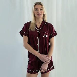 May include: Burgundy satin pajama set with white piping and the letters "AΦ" embroidered on the chest.