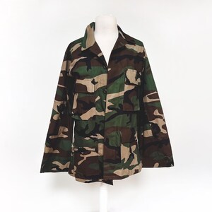 Puede incluir: Una chaqueta de camuflaje con cierre de botones y varios bolsillos.