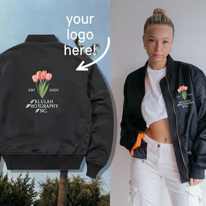 Könnte beinhalten: Schwarze Bomberjacke mit einem Blumendesign und dem Text "EST. 2020 ALULAH PHOTOGRAPHY INC." auf der Rückseite.