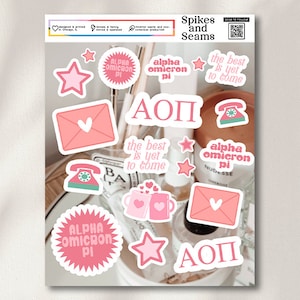 May include: A set of pink and white stickers featuring the Greek letters "AOP" and the phrase "alpha omicron pi". The stickers also include a star, a phone, a heart, and an envelope.