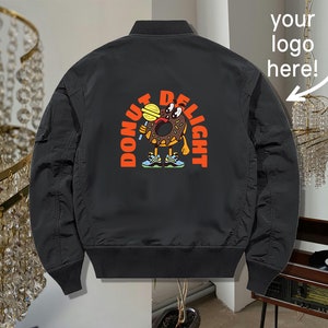 May include: Black bomber jacket with a donut character graphic on the back. The graphic says "Donut Delight" and features a donut with eyes, a mouth, and arms holding a lollipop.